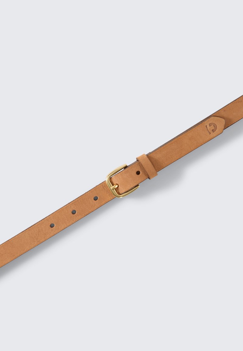 Yksinkertainen ruskeasta nahasta valmistettu vyö, jossa on kullattu metallinen solki. Vyössä on tasaisesti sijoitettuja reikiä ja logon kohokuviointi hihnassa. Sileä pinta, klassinen muotoilu.