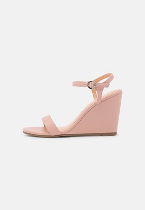 Pink wedge sandals with a smooth synthetic upper, thin straps, and a buckle closure. Features a wide wedge heel and flat sole.