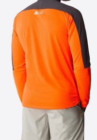 Long-sleeve shirt in bright orange with gray accents. Fabrics appear textured with a logo at the upper back. Standard fit.