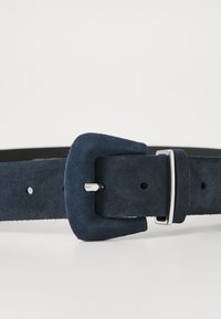 Cintura in suede navy con fibbia rettangolare, gancio metallico e molteplici fori per la regolazione. Texture liscia con un interno a contrasto neutro.