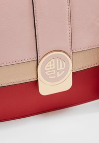 Wielokolorowa skórzana torba na ramię z różowym górnym fragmentem, beżowym środkowym paskiem i czerwonym dnem. Wyróżniające się złote okucia z logo.