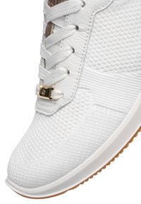 Weißer gestrickter Sneaker mit weißen Schnürsenkeln, goldfarbener Schnürsenkel-Verriegelung, Lederöse und hellbraunem Gummi-Außensohlenrand.