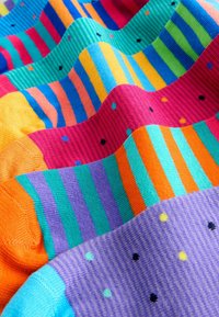 Kleurige sokken met horizontale strepen in meerdere kleuren: oranje, roze, paars, turquoise en groen, met af en toe stippen.
