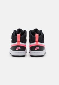 Svartvita högtoppsneakers med rosa detaljer, som har en meshuvuddela, vadderad krage och Nike-logotyp på hälen och remmen.