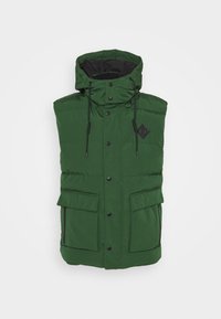 Vihreä toppaliivi, jossa on korkea kaulus, mustat yksityiskohdat, säädettävät kiristysnyörit ja kaksi etutaskua. Materiaali näyttää sileältä ja kestävältä.