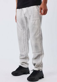 Joggers in denim grigio con una finitura sbiadita, dotati di tasche cucite e una vestibilità comoda, abbinati a sneaker sportive nere.