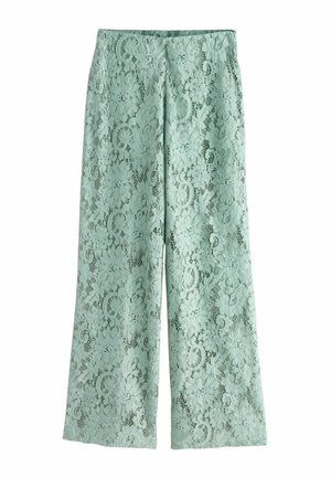 Jasnozielone spodnie z szerokimi nogawkami z kwiatową koronkową nakładką oraz wysokim pasem, ułożone płasko na białym tle.