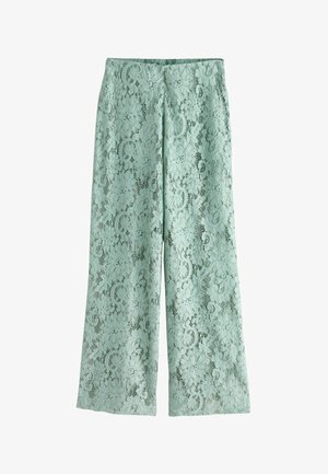 Pantaloni largi de culoare verde deschis, cu o suprapunere florală din dantelă și talie înaltă, așezați pe o suprafață albă.