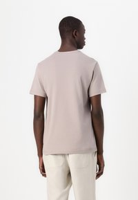 Light gray short-sleeve t-shirt made of soft cotton, featuring a crew neck and a relaxed fit, worn with beige pants.