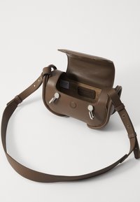 Geantă din piele maro tip crossbody cu un design rotunjit, închideri din metal argintiu, curea ajustabilă și un interior simplu.