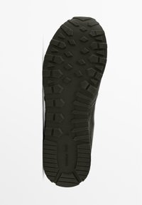 Gumová podrážka boty se vzorovaným běhounem obsahujícím hexagonální a obdélníkové prvky, tmavě šedá barva s viditelným nápisem značky.