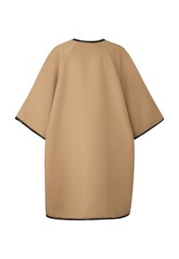 Beige oversized beklædningsgenstand med korte ærmer, lavet af blødt stof. Har en sort kant langs kanterne og en rundet halsudskæring.