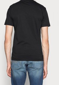 Svart bomull t-shirt med rund halsringning och korta ärmar, tillsammans med blå denimjeans. Enkelt mönster, inga synliga motiv eller logotyper.