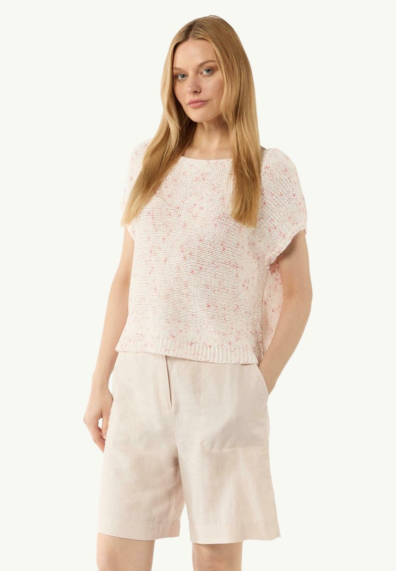 Hellrosa Strickpullover mit lockerer Passform, strukturiertem Design und weißen Sprenkeln; kombiniert mit hellbeigen Leinen-Shorts.