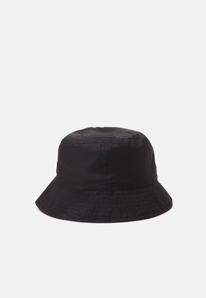 Zwarte stoffen bucket hat met gestikte naden en een licht uitlopende rand, getoond tegen een effen lichtgrijze achtergrond.