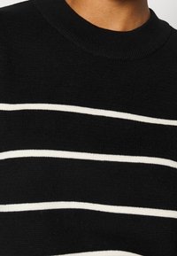 Maglione nero a maglia con strisce bianche orizzontali, scollatura rotonda, tessuto testurizzato e polsini e orlo a coste.