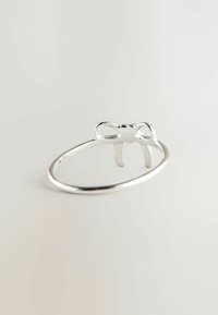 Silver ring featuring a bow design at the top, smooth surface, thin band, and polished finish. Minimalist aesthetic with a delicate structure.