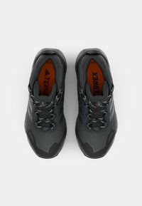Sorte svarte joggesko med teksturert overdel, grå detaljer og lyseblå snører. De har en polstret såle og et robust såledesign.