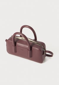Mauve krāsas ādas somiņa ar divām noapaļotām rokturiem, ar rāvējslēdzēju aizdari un taisnstūra formu. Izceļas ar gludu tekstūru un diskretu zīmola detaļu sānos.