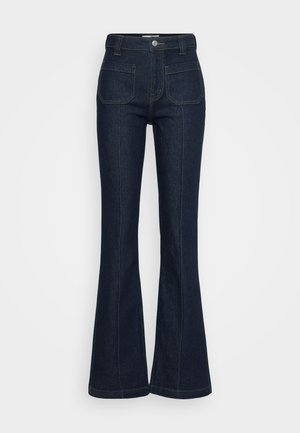 Mørkeblå høy midje denim jeans med patch lommer foran, knapp og glidelås lukking, og utslåtte ben på en lys bakgrunn.