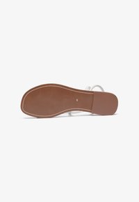 Hvide sandaler med dobbelte remme, flad brun gummisål og en glat overflade. Størrelse angivet som 40 på sålen.