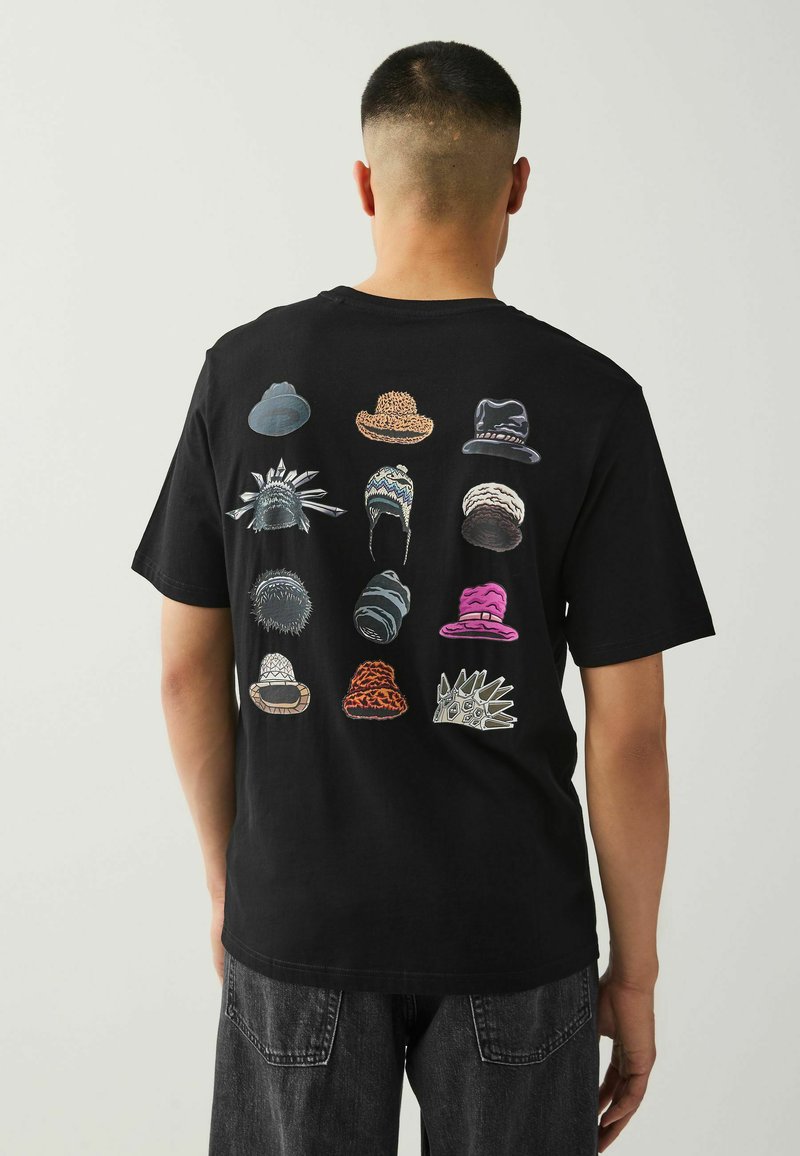 T-shirt nera con una grafica di vari cappelli in diverse forme, colori e texture stampata sul retro.