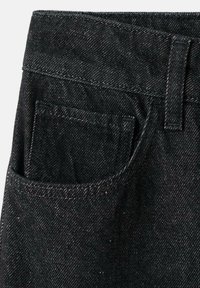 Primer plano de una tela de denim negro que presenta un bolsillo frontal, costuras cosidas y una cintura con un ojal para el cinturón, mostrando un acabado texturizado.
