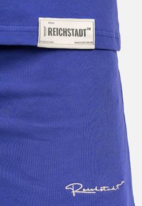 Blauw katoenen shirt met een gestructureerde afwerking, voorzien van een logo-label en geborduurd detail. Korte mouwen en een ontspannen pasvorm.