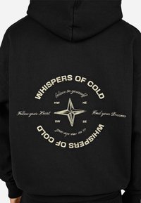 Μαύρη φόρμα με κουκούλα, η οποία διαθέτει μια κρεμ σχεδίαση πυξίδας στην πλάτη με το κείμενο "ΨΙΘΥΡΟΙ ΨΥΧΡΑΣ" και περιβάλλεται από ενθαρρυντικές φράσεις.