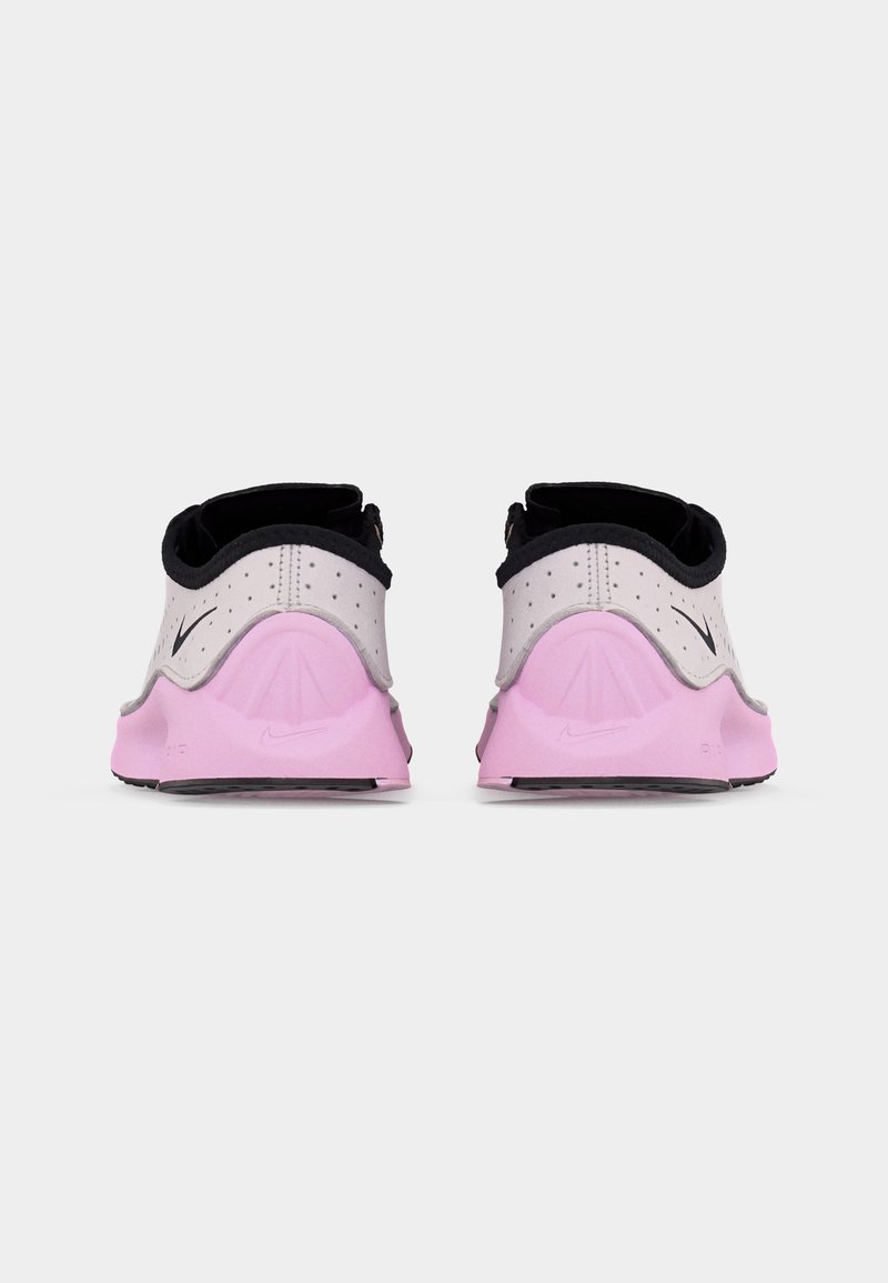 Slechts een paar lage sneakers gezien van achteren, met witte bovenkanten met zwarte bies en roze zolen met Nike-logo's.