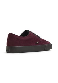 Bordeauxfarbene Wildledersneakers mit niedrigem Profil, schwarzen Schnürsenkeln und einer strukturierten schwarzen Gummisohle. Mit einem dezenten Logo an der Seite.