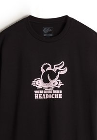 Schwarzes Baumwoll-T-Shirt mit einem rosa Grafik eines Cartoon-Charakters mit lockigem Haar, neben dem Text "DU WIRST ZU EINEM KOPFZERBRECHEN."