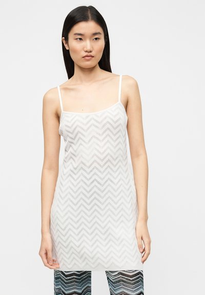 Débardeur blanc en maille avec un motif en chevrons, doté de fines bretelles et d'une coupe ample, associé à un pantalon à motifs multicolores.