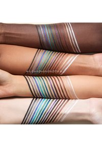 Fünf Arme zeigen mehrfarbige Make-up-Linien in verschiedenen Farbtönen, darunter Braun, Blau, Grün und Metallic, mit numerischen Beschriftungen darunter.