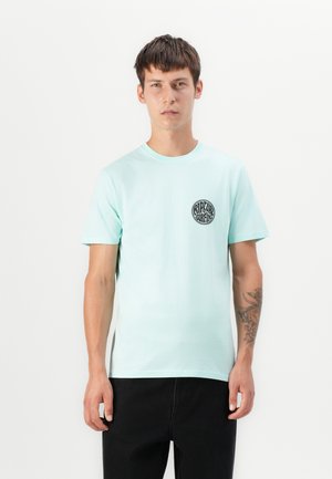 T-shirt en coton vert menthe avec des manches courtes et un col rond ; présente un logo noir circulaire sur la zone gauche de la poitrine.