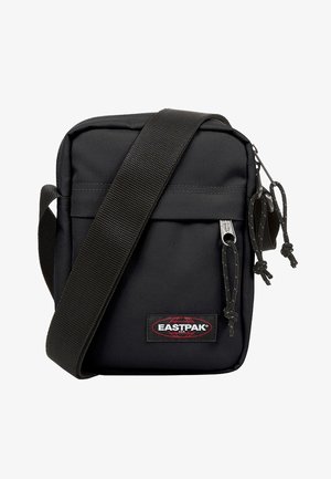Sacoche bandoulière Eastpak noire compacte avec poche avant zippée et bandoulière large réglable.