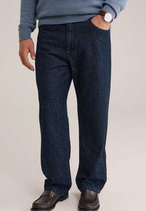 Blue denim jeans featuring a straight leg design, two side pockets, and subtle texture. Worn with brown leather slip-on shoes.