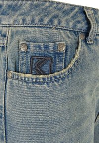 Jeans de mezclilla azul con una textura desteñida, un pequeño bolsillo frontal con logo bordado y remaches metálicos. Diseño clásico de cinco bolsillos.