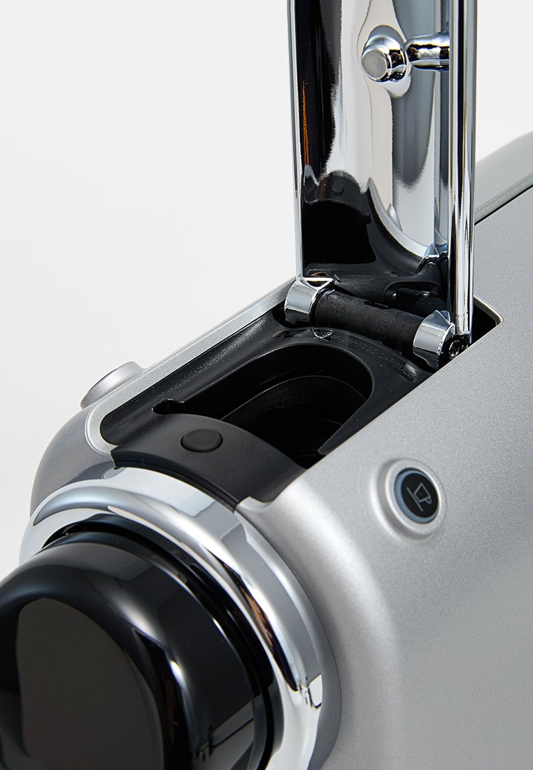 Appareil en argent avec une poignée en chrome, un bouton noir circulaire et des boutons de contrôle ; dispose d'un compartiment ouvert révélant le mécanisme interne.