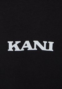 Black cotton fabric with a white, bold "KANI" logo in a sans-serif font. The design is simple and text-centric, emphasizing the brand name.