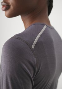 Dark gray fitted shirt with short sleeves, featuring a textured fabric and contrasting light gray stitching along the shoulder seam.
