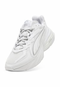 Weißer Sportschuh aus Mesh- und Leder-Material, mit runder Form, dicker Sohle und strukturierten Details sowie dezenten Markenzeichen.