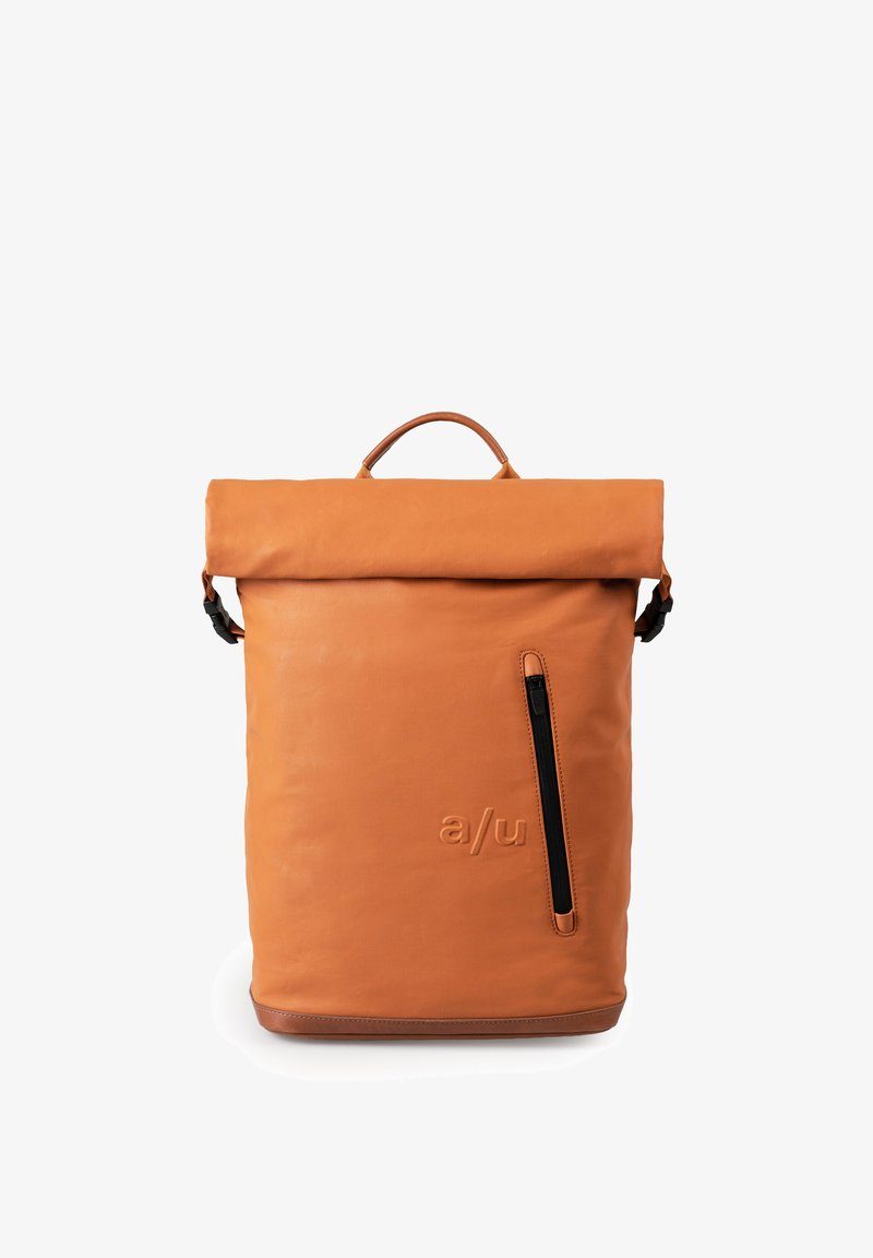 Zaino arancione in pelle con apertura a rullo, manico superiore, tasca laterale con zip, logo impresso e una texture liscia. Base scura e arrotondata.
