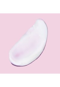 Échantillon de texture cosmétique crémeuse blanche et rose clair sur un fond rose, lisse avec une finition brillante et un léger éclat.