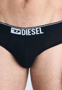 Zwarte mannenonderbroeken met een brede elastische tailleband met het "DIESEL" logo in het wit. Gladde stof, klassieke snit en aansluitende pasvorm.