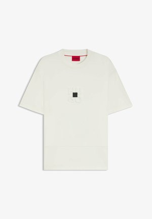 Crème-kleurig t-shirt, korte mouwen, ronde hals, met reliëflogo op de borst en een rechthoekige zwarte accent. Zachte jersey stof.