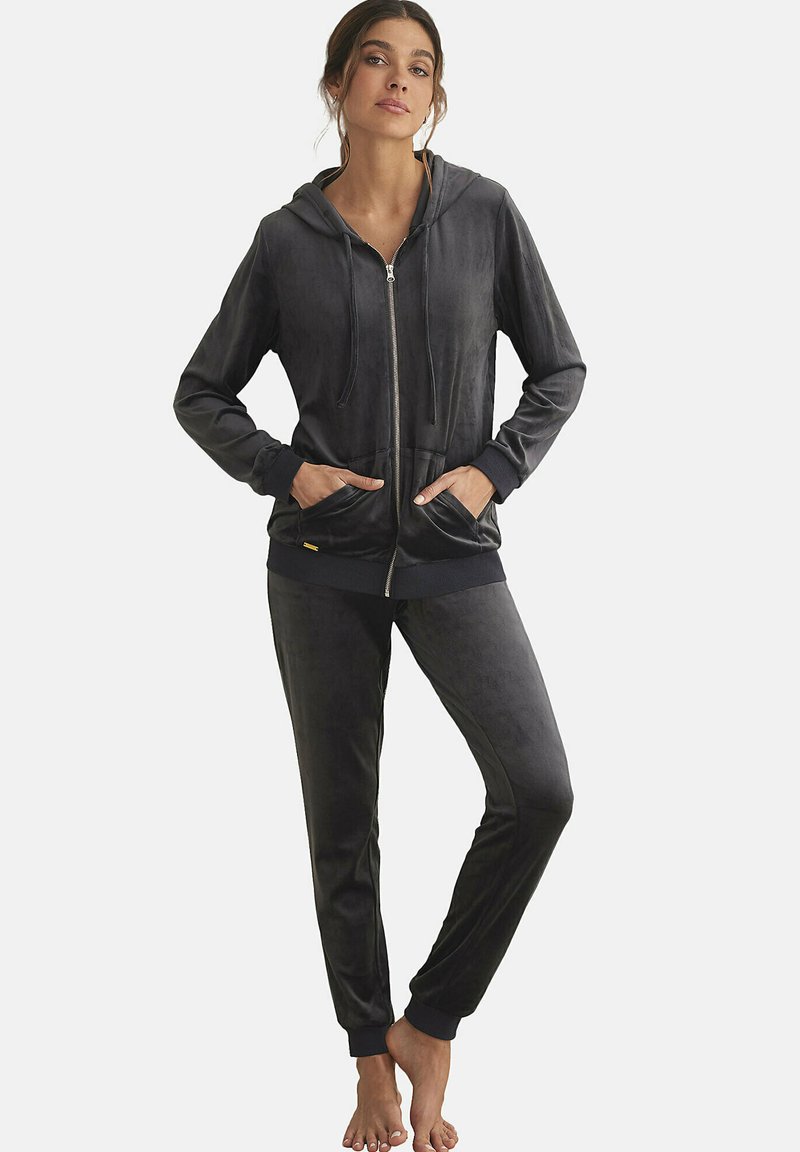 Zwarte velours trainingspak met een zip-up hoodie met zakken en bijpassende tapered broek. Zachte textuur met geribbelde manchetten en tailleband.