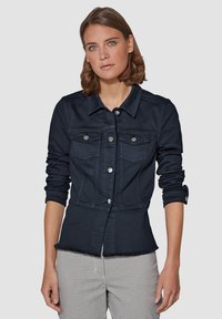 Marineblauwe denimjas met kraag, knoopsluiting, twee borstzakken en een getailleerde taille. Kenmerkt omgeslagen mouwen en een rafelige zoom.