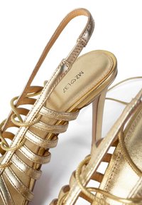 Sandale cu toc înalt aurii, prezentând un design cu curea împletită, material lucios, vârf ascuțit și un toc subțire de tip stiletto.