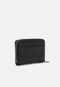 Portefeuille en cuir noir avec surface texturée, doté d'une fermeture zippée et d'un emplacement pour cartes à l'extérieur. Design minimaliste avec des accents en matériel doré.